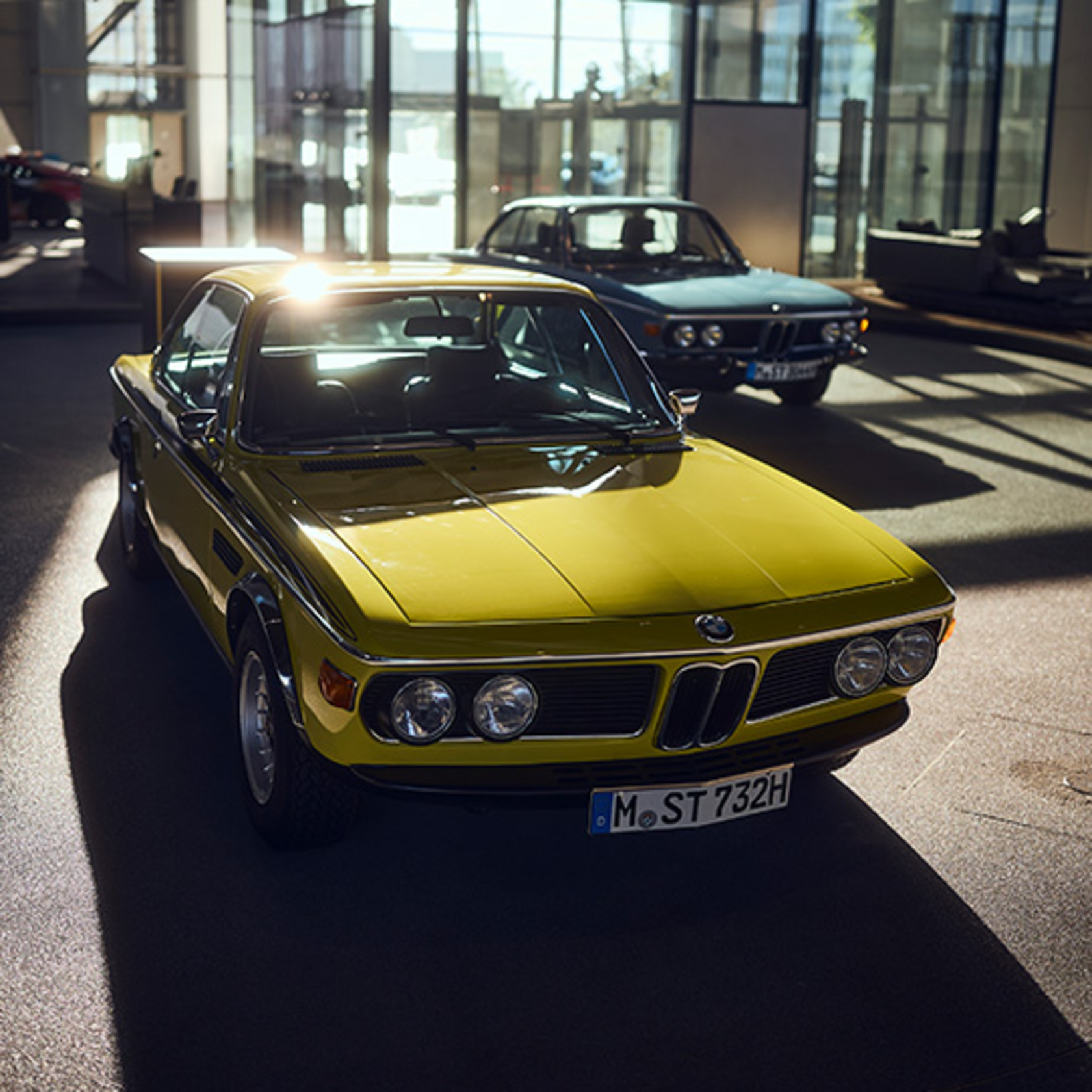 ein gelber BMW Oldtimer steht im Gegenlicht in der BMW Welt