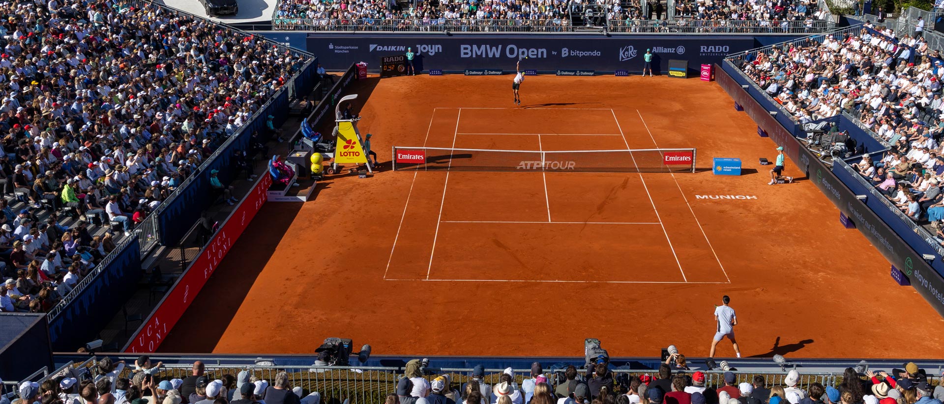 Ein Blick von oberhalb der Tribüne auf einen orangenen Tennisplatz