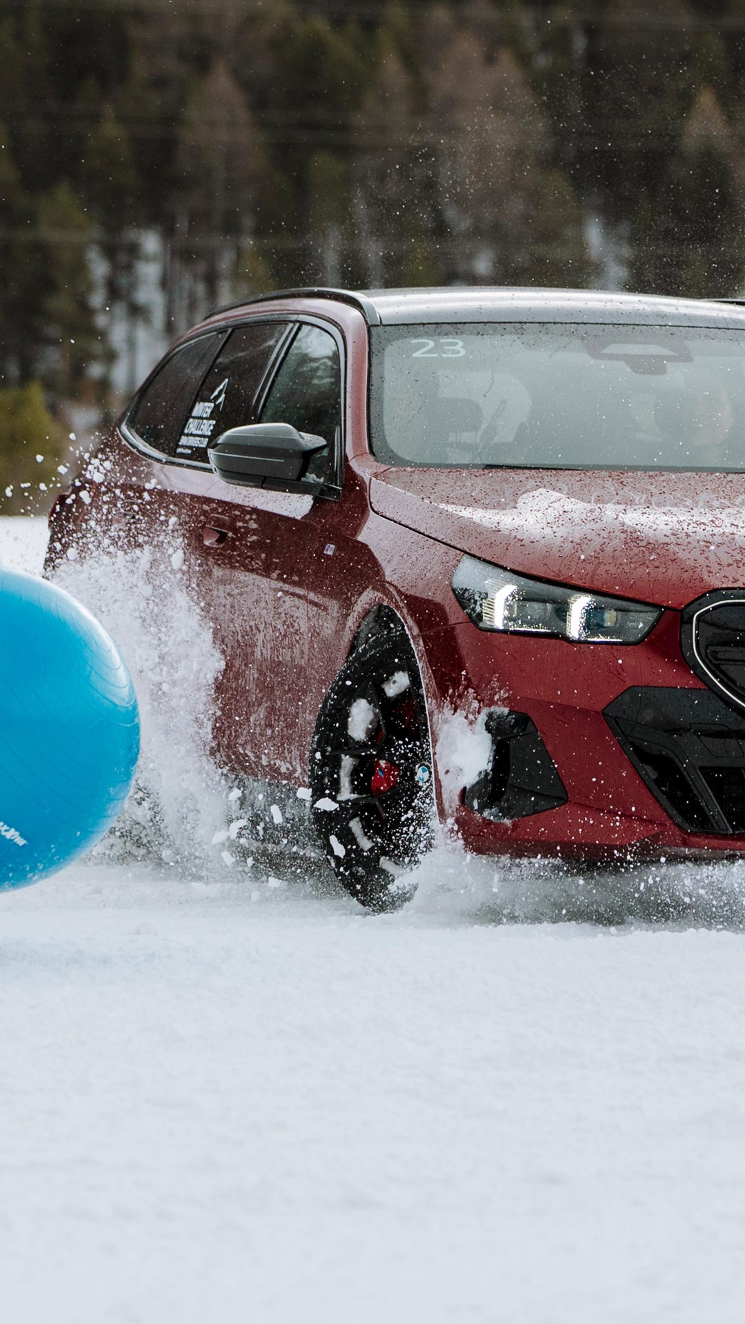 Ein roter BMW versucht im Schnee einem blauen Ball auszuweichen