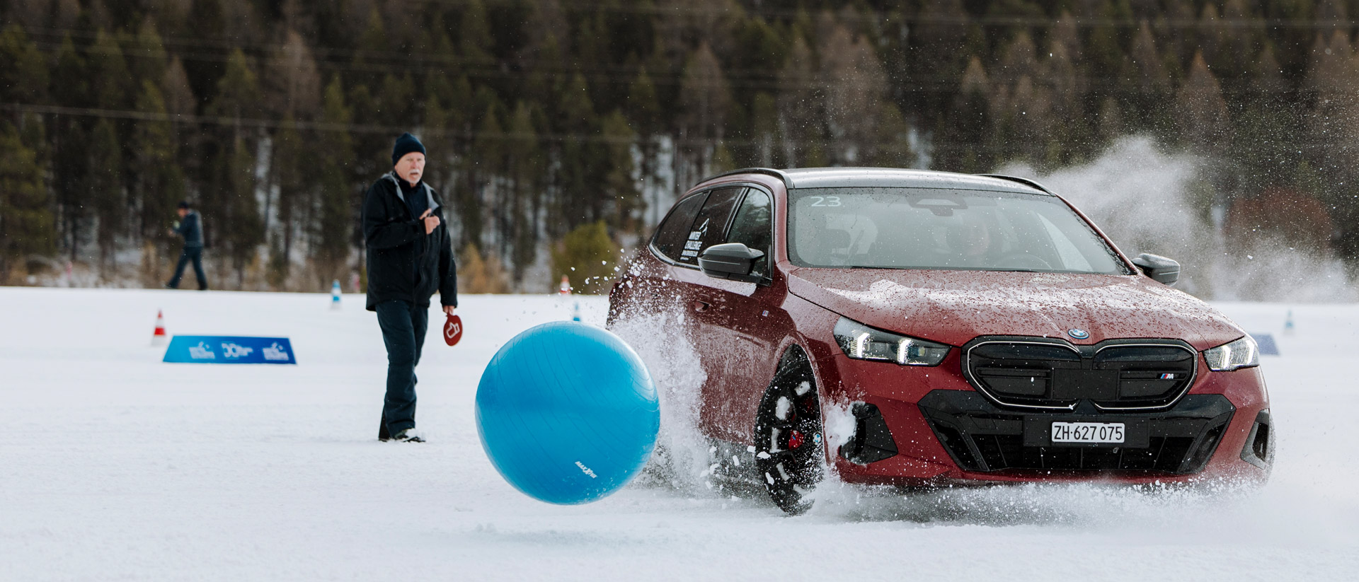 Ein roter BMW versucht im Schnee einem blauen Ball auszuweichen
